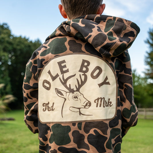 Camouflage hoodie with 'Ole Boy' logo on the back, worn by a person outdoors.