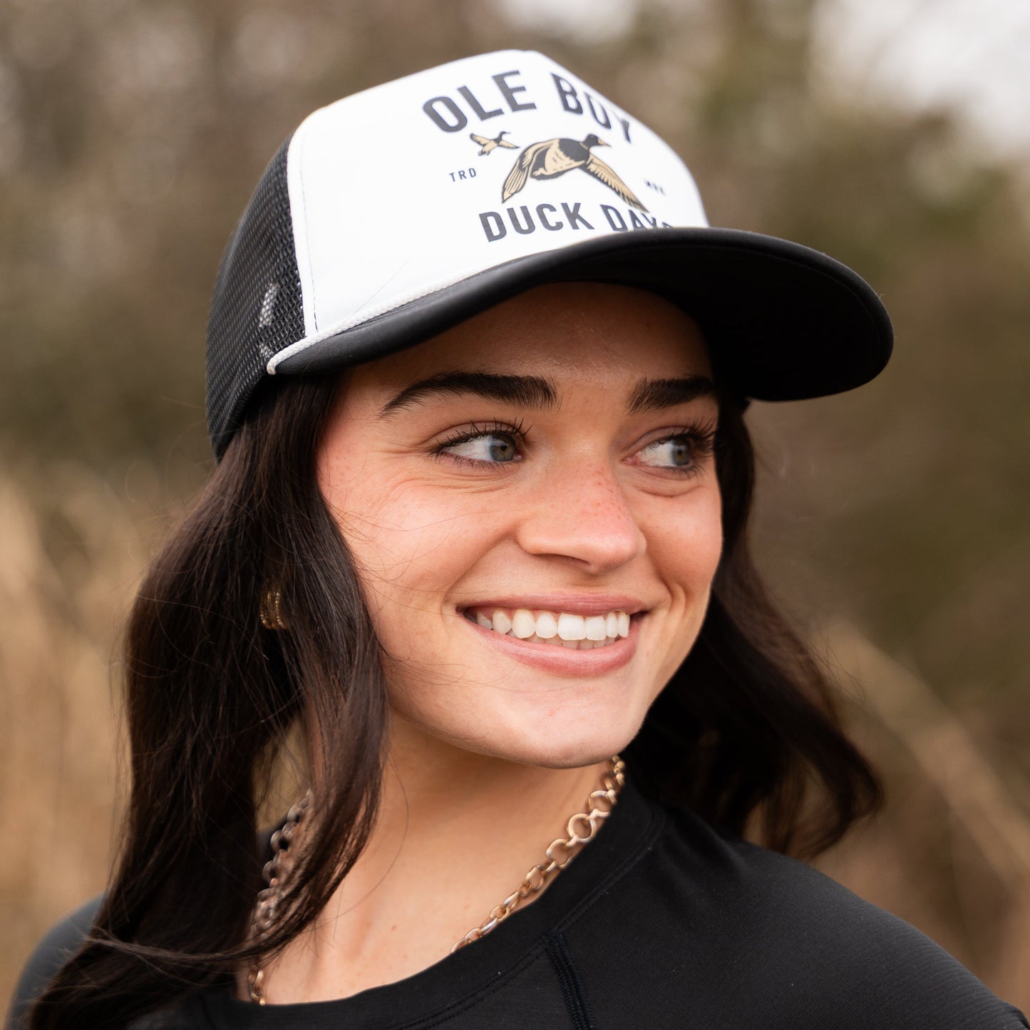 Woman wearing a cap with 'OLE BOY DUCK DAYS' text and logo outdoors