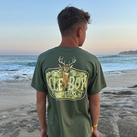Person wearing a green Ole Boy  t-shirt with a graphic design on a beach