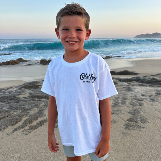 Child wearing a white Ole Boy Bass t-shirt with text on a beach