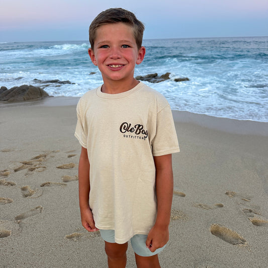 Child wearing a 'Ole Boy' shirt on a beach