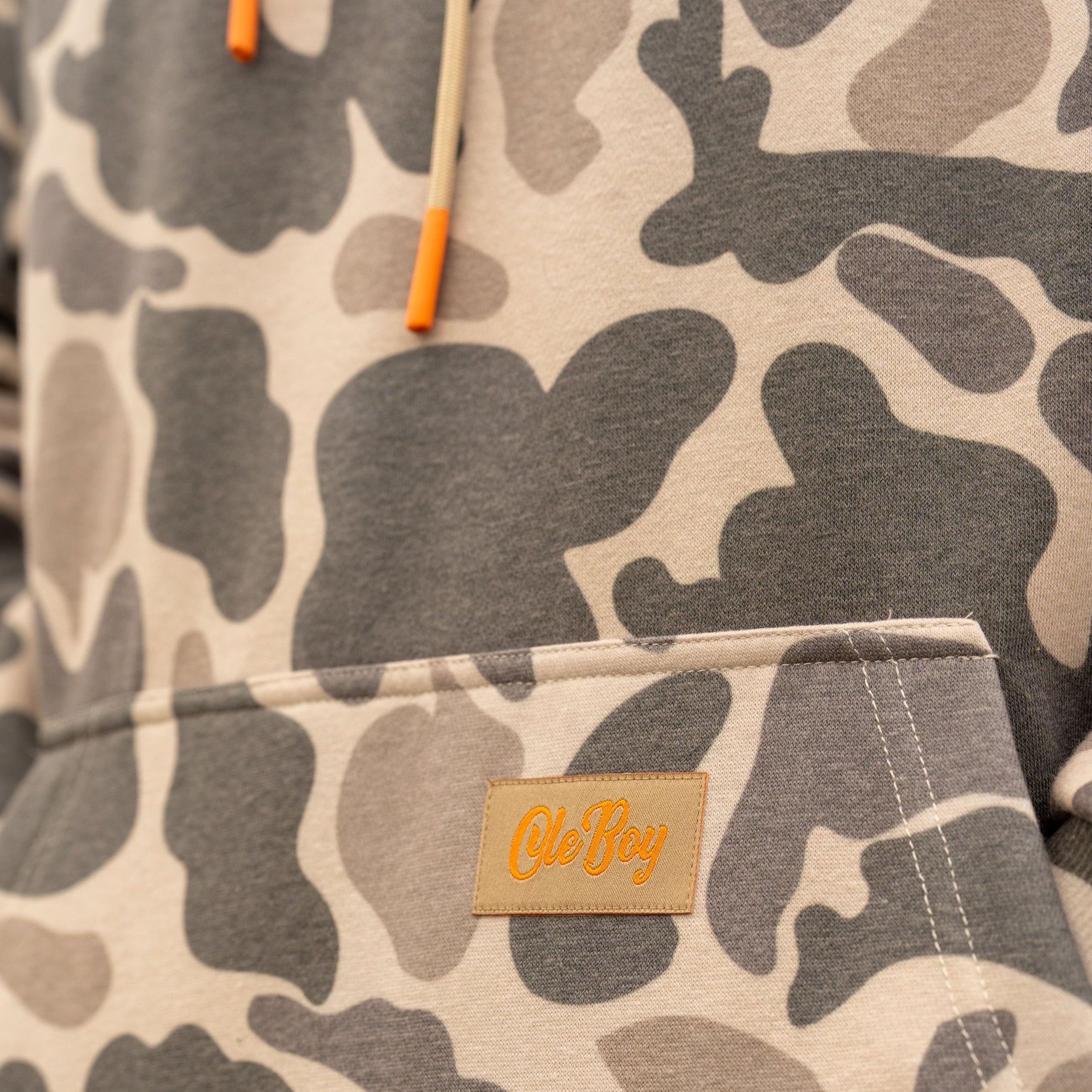 Camouflage-patterned fabric with a brand label on a neutral background
