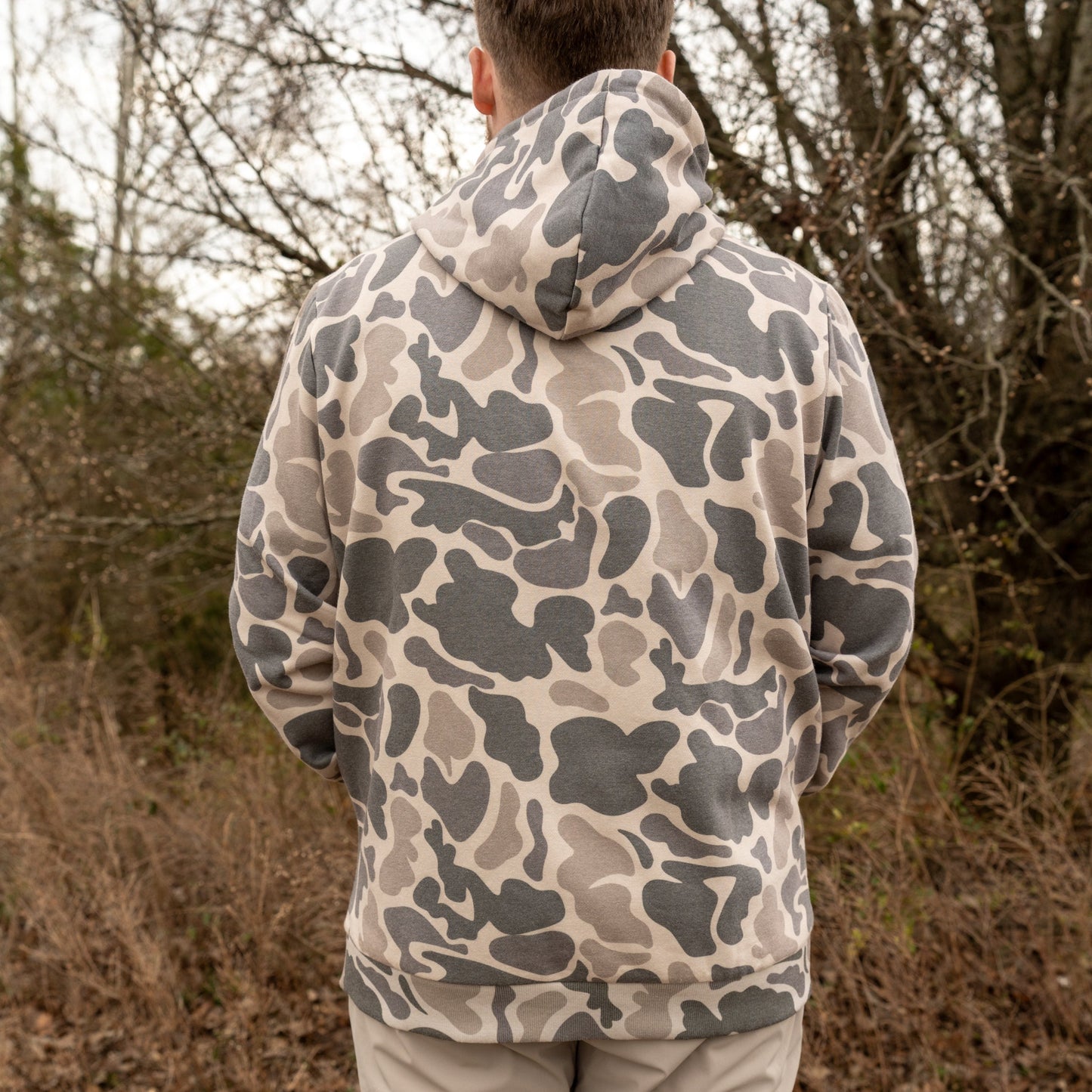 Person wearing a camouflage hoodie standing in a forested area