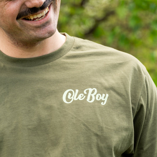 Man wearing a green t-shirt with 'Ole Boy' text, outdoors.