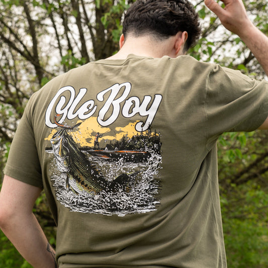 Person wearing a green t-shirt with 'Ole Boy' and fish graphic on the back, outdoors.