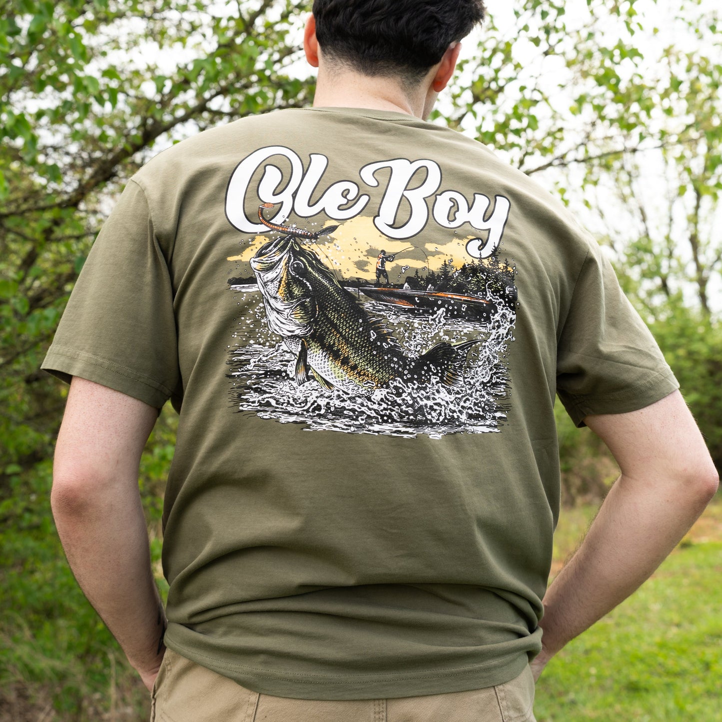 Person wearing a green t-shirt with a graphic design and text outdoors