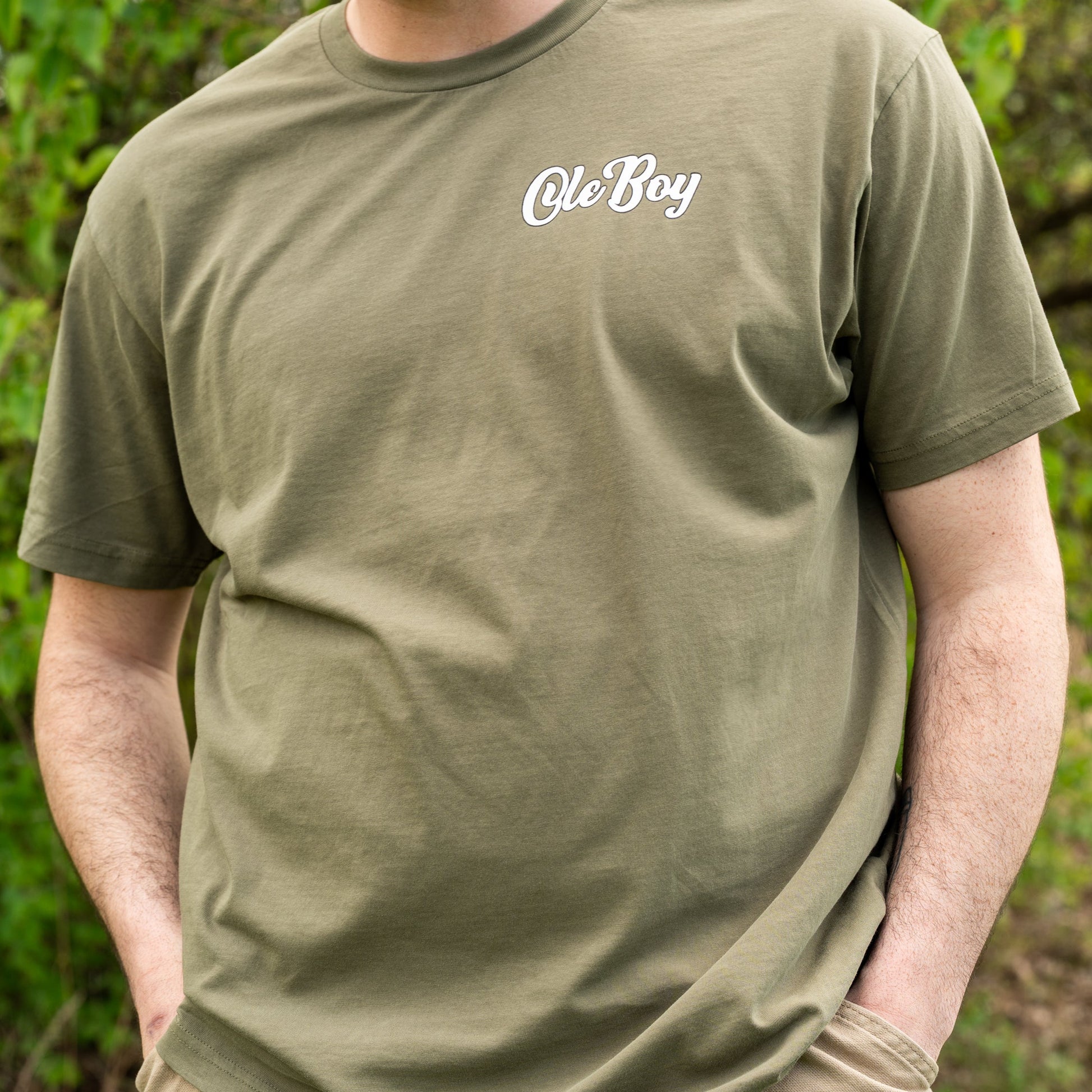 Person wearing a green t-shirt with 'Ole Boy' text in a natural setting