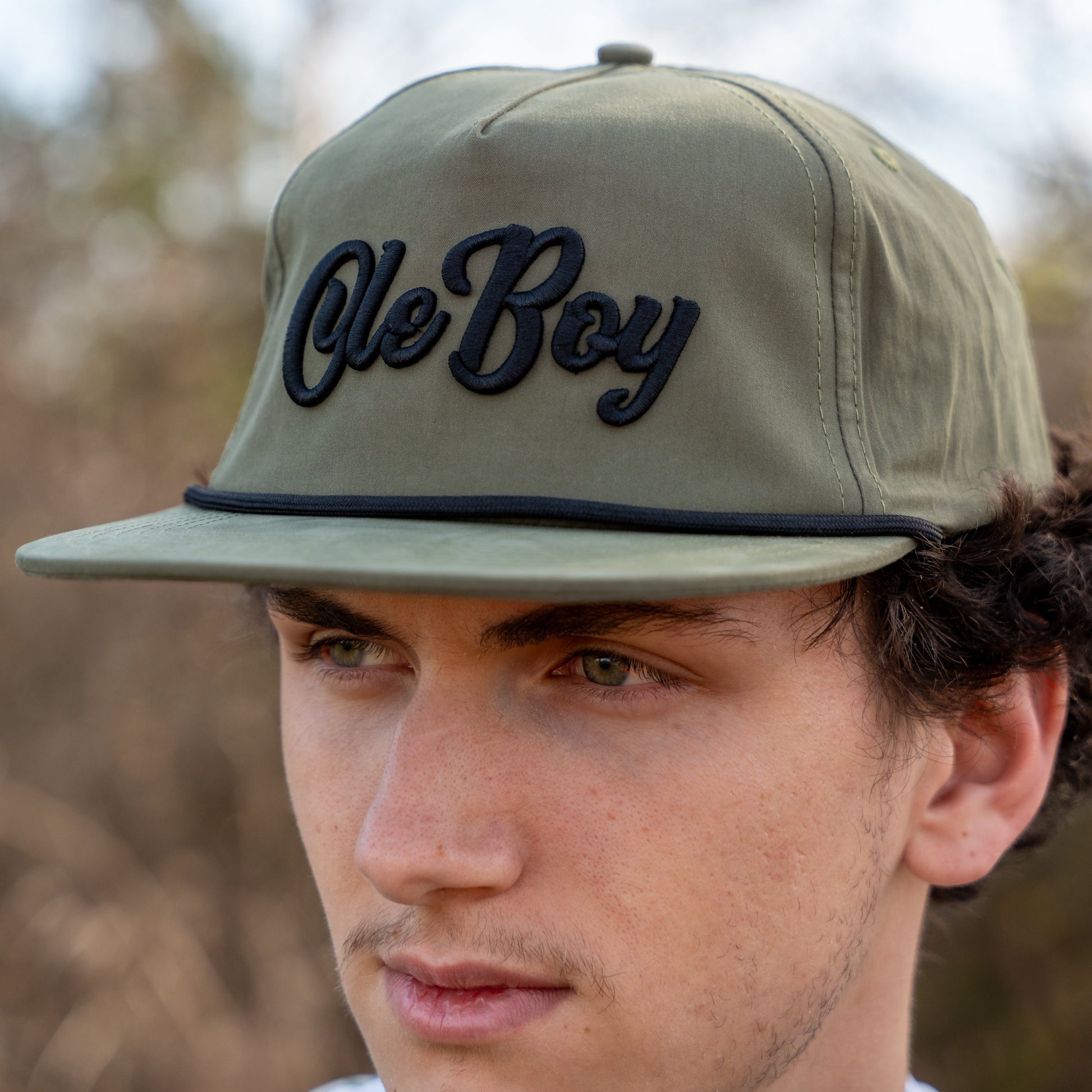 Person wearing a cap with 'Ole Boy' text outdoors