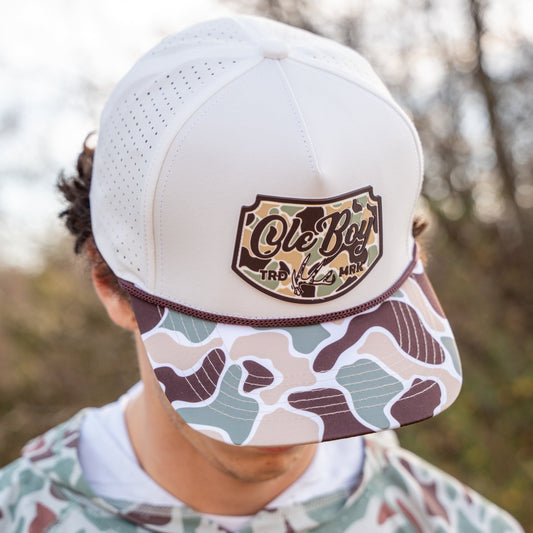 Person wearing a white cap with a camouflage pattern and 'Ole Boy' logo, outdoors.
